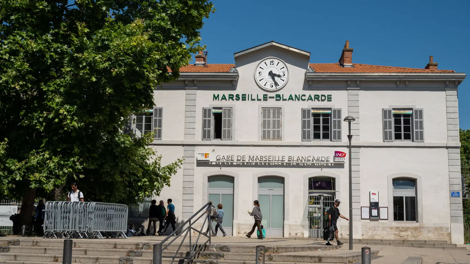 Voyageurs devant la gare de Marseille-Blancarde par temps clair