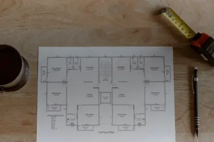Plan de maison, mètre et crayon posés sur une table