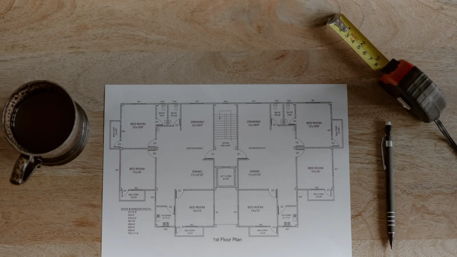 Plan de maison, mètre et crayon posés sur une table