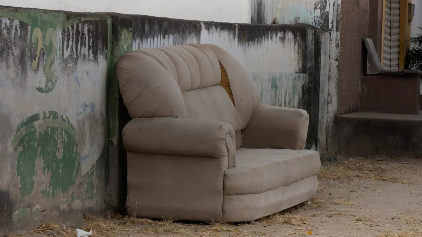 Un vieux canapé abandonné contre un mur : le dépôt à éviter