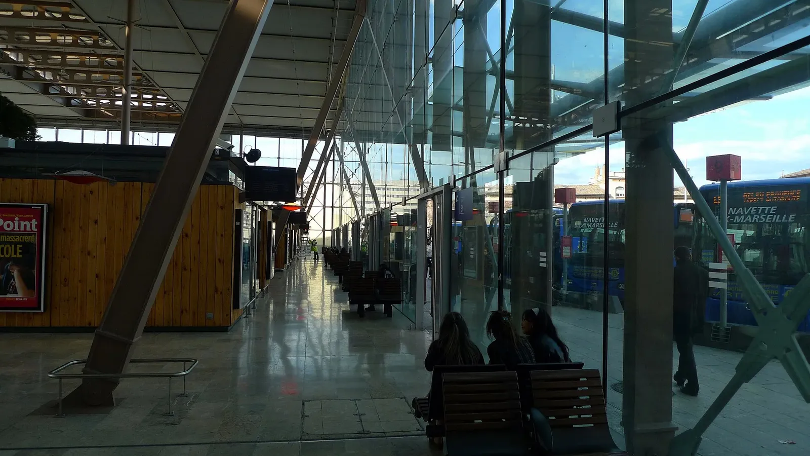 Salle d'attente côté gare routière dans le hall de la gare Saint-Charles, avec les autocars derrière les vitres
